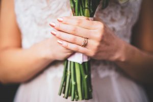brides hands holding bouquet with rose ring